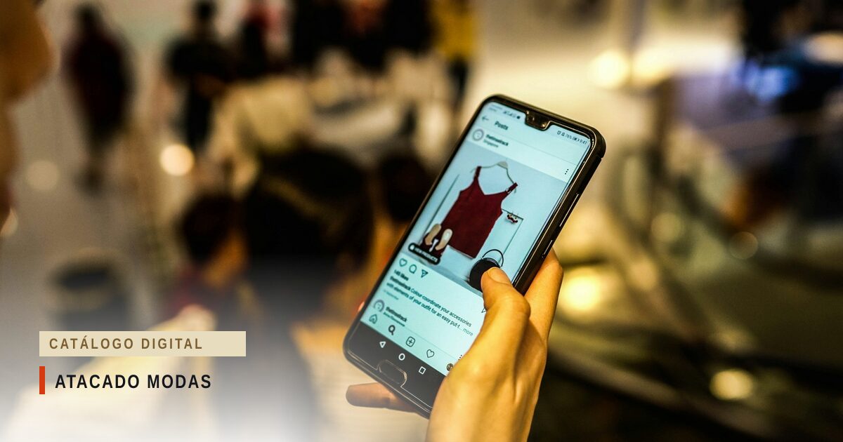 Mão segurando um celular que exibe o anúncio de uma blusa vermelha, com uma loja desfocada ao fundo