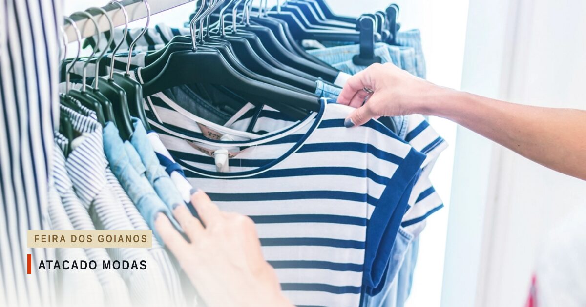 Mãos escolhendo uma camiseta listrada de azul e branco numa arara de roupas com cabides pretos