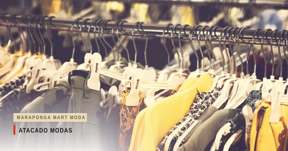 Araras de loja cheias de roupas em cabides brancos, com peças amarelas, cinza e estampadas em primeiro plano