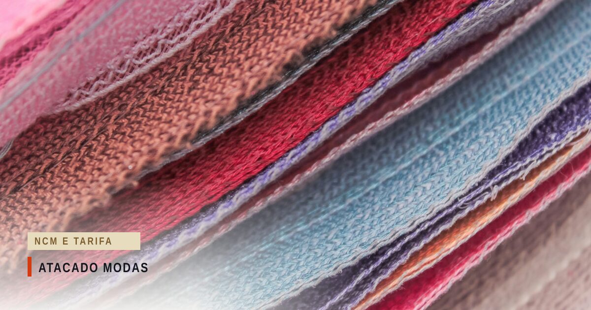Close de várias peças de malha empilhadas e vistas de perfil, em rosa, vermelho, azul-claro e lilás, com o ponto do tecido e as barras costuradas à mostra