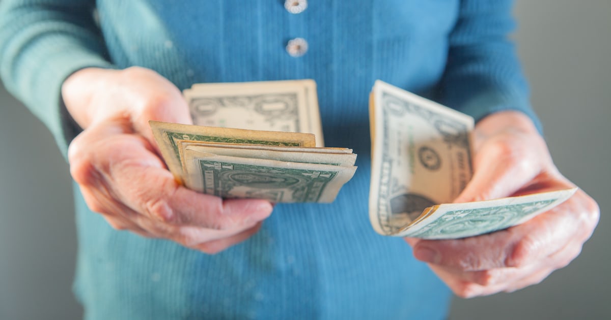 Mãos segurando notas de dólar americano, na contagem típica de quem se prepara para compras em espécie