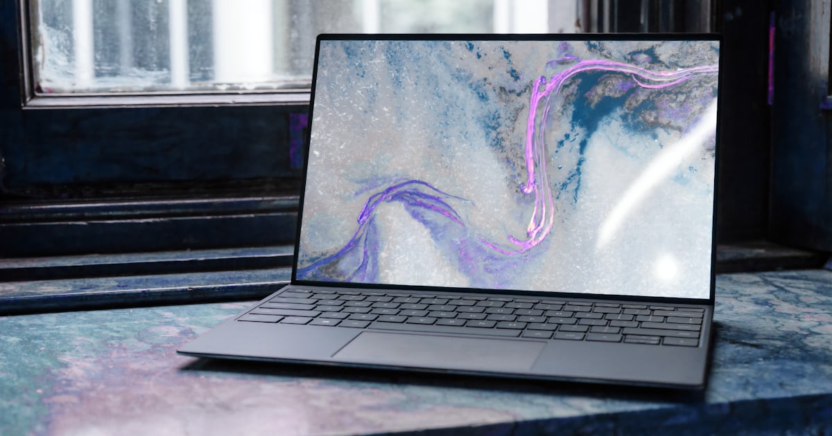 Notebook aberto sobre bancada ao lado de componentes de computador, no contexto típico de compra de informática